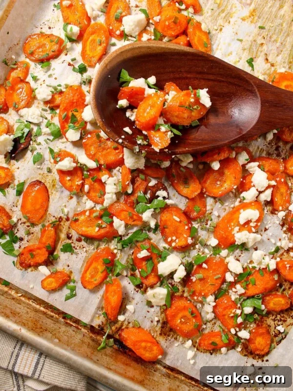 A sheet pan with sliced roasted carrots made with hot honey and sprinkled with feta cheese, chives and parsley.