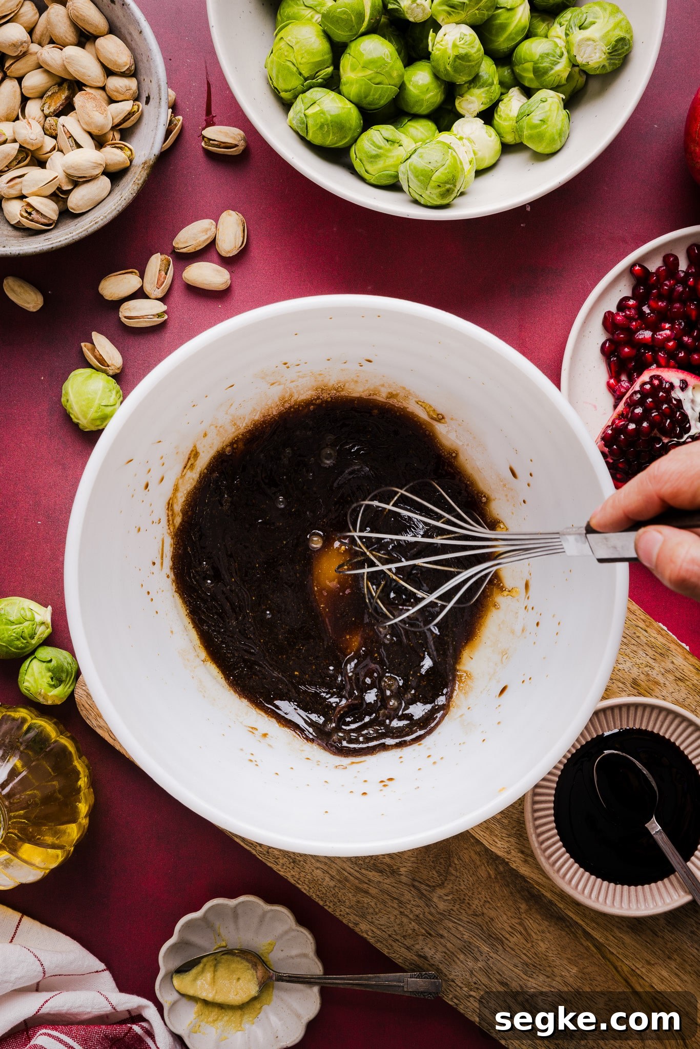 Maple syrup, balsamic vinegar, soy sauce, garlic and oil being whisked together in a bowl.