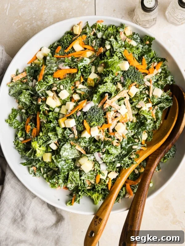Kale and broccoli salad in a large bowl with wooden salad spoons.