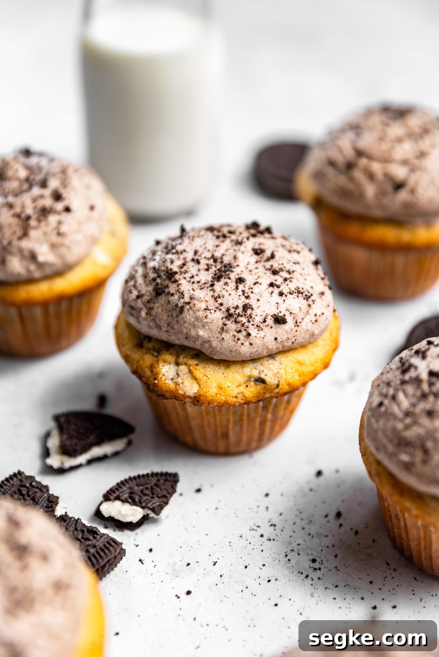 Oreo Cupcakes with Whipped Oreo Cream Frosting 9 Oreo cupcakes with oreo whipped cream frosting next to a glass of milk and oreo cookies