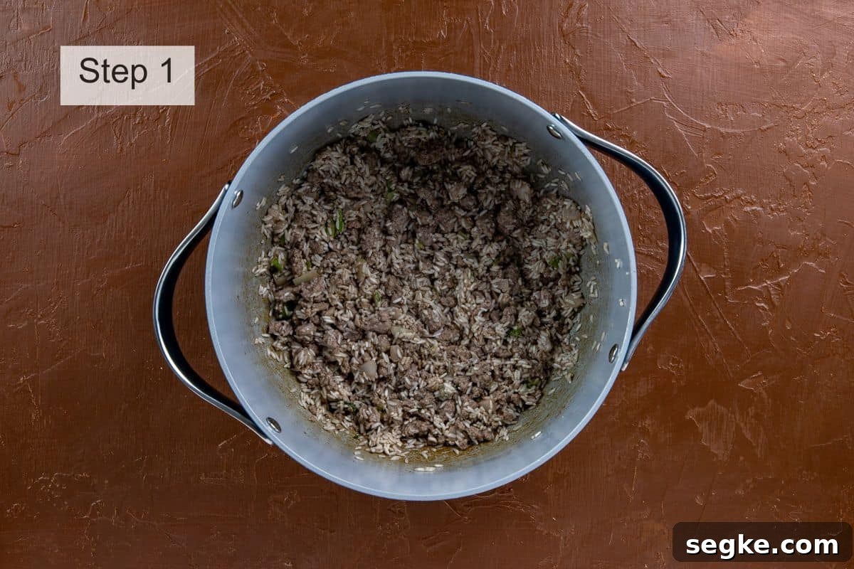 Ground beef, rice, onion, bell pepper, and celery browned in a pot.