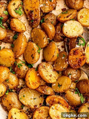A spoon digging into roasted potatoes.