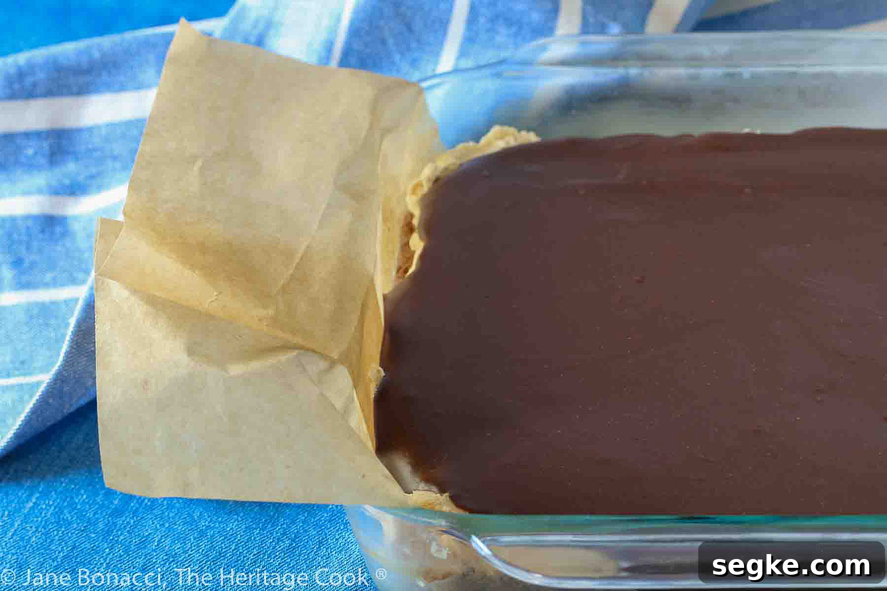 Whole block of brownies ready for cutting; showing parchment sling used to lift them out of the pan.