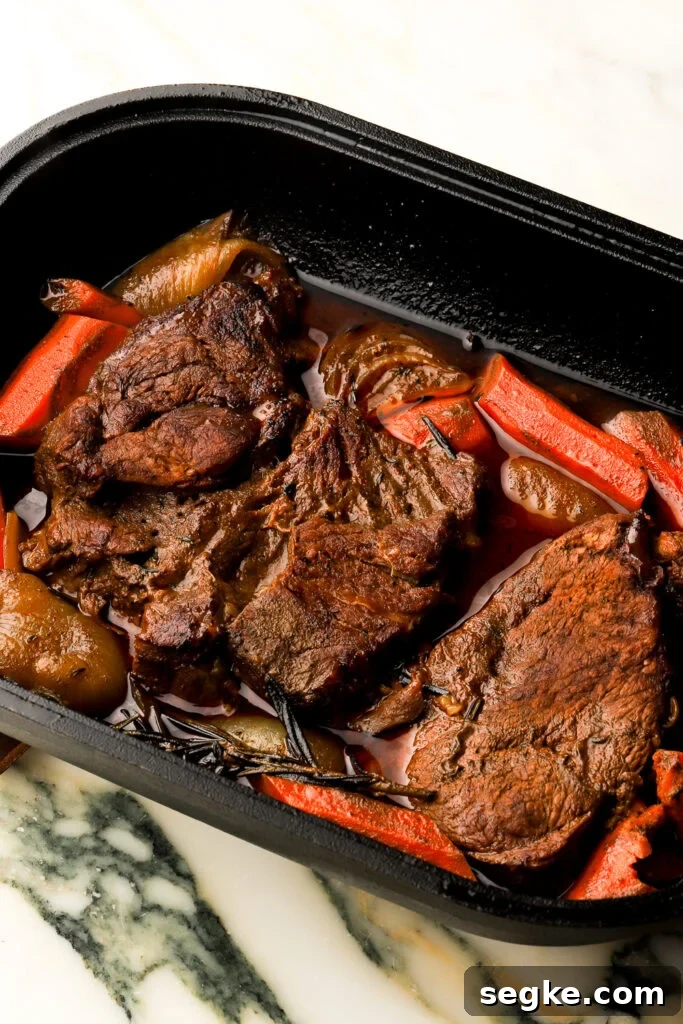 Everyday Braised Beef Recipe for Weeknight Dinners 2 braised beef after it's finished cooking with carrots and broth in a cast iron