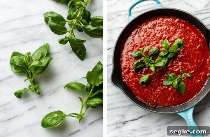 adding basil sprigs to a cast iron skillet with marinara sauce