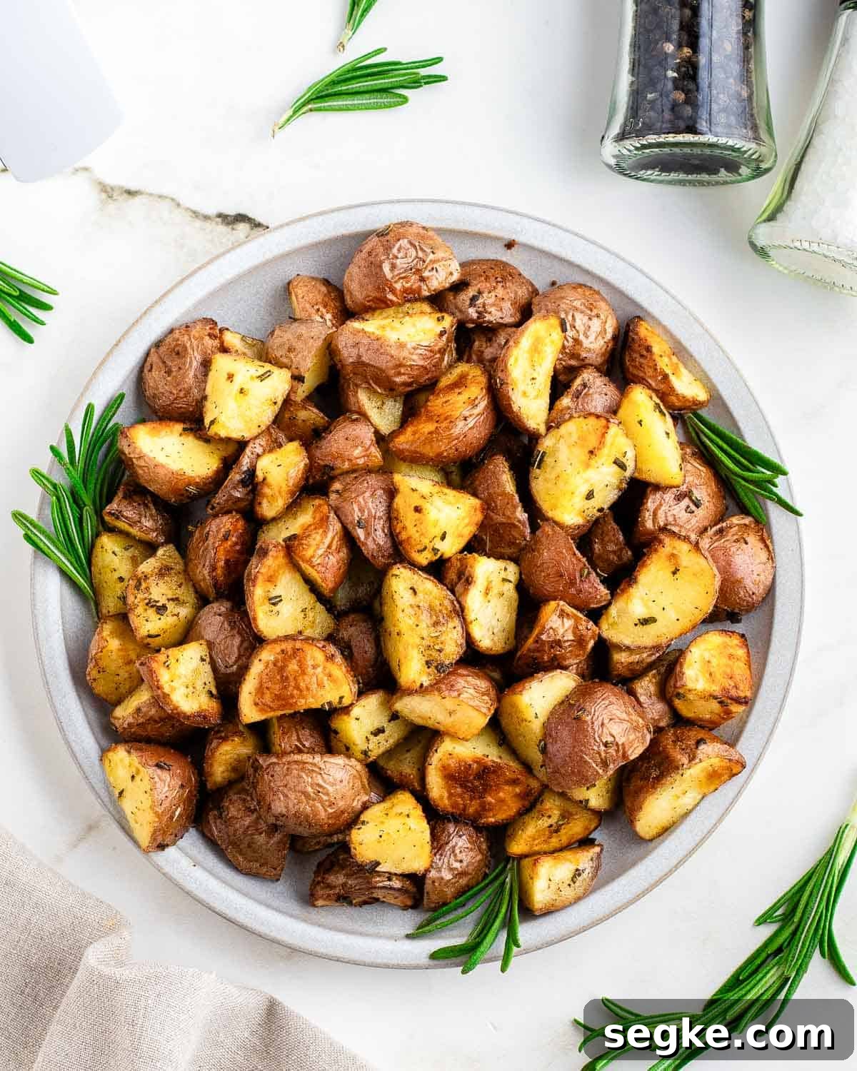 Perfectly Crispy Air Fryer Red Potatoes 5 Roasted air fryer red potatoes on a white plate garnished with fresh rosemary.