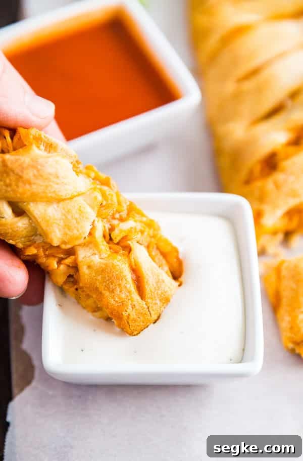 Cheesy Buffalo Chicken Puff Pastry Braid 4 A hand dipping a piece of Buffalo Chicken Braid into ranch dressing.