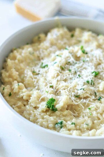 garlic parmesan risotto in white bowl topped with parmesan cheese and parsley