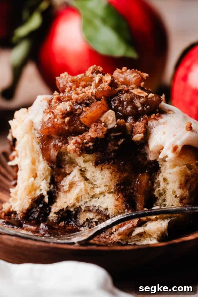 Apple Pie Cinnamon Rolls with Apple Cider Caramel Bottoms 14 A close-up of a cinnamon roll with a big bite missing, showing the gooey insides.