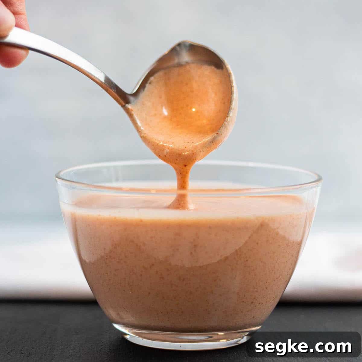 A glass bowl of yum yum hibachi sauce with a ladle. 