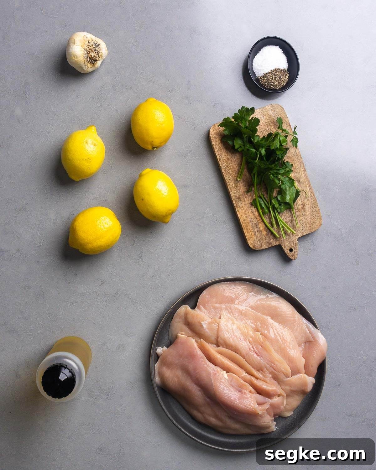 How to Make Juicy Marinated Grilled Chicken 4 Ingredients shown: garlic, salt, pepper, lemons, parsley, olive oil, and chicken cutlets.