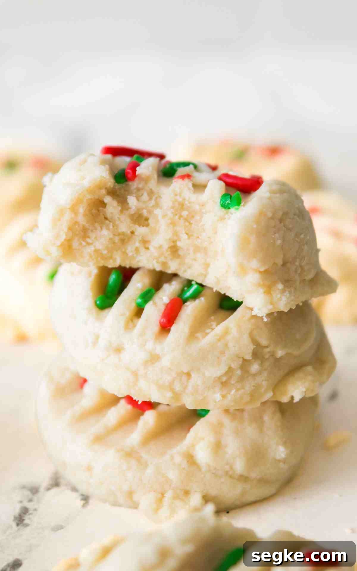 Light, Fluffy Whipped Shortbread Cookies Recipe 2 A stack of whipped shortbread cookies with Christmas sprinkles.