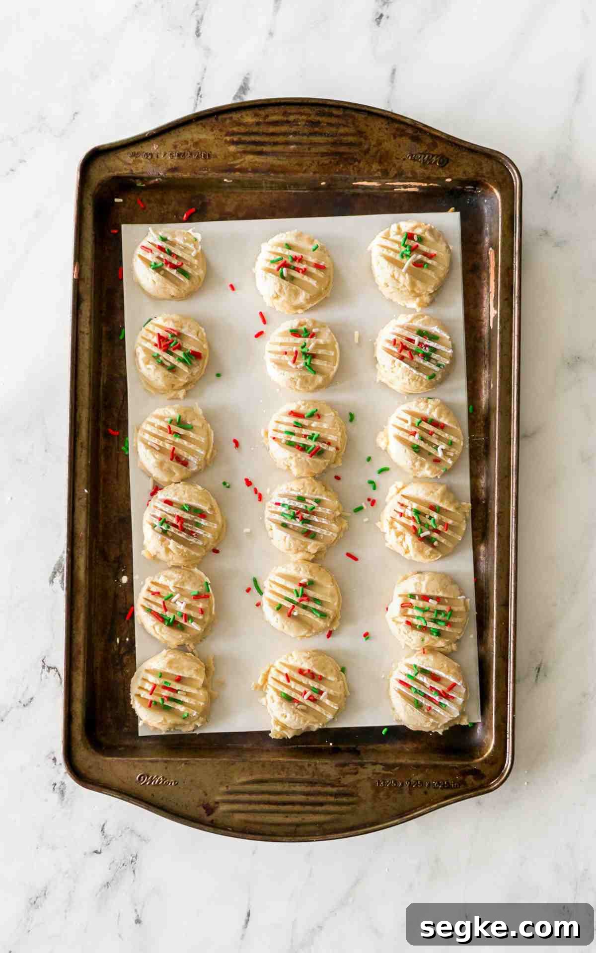 Light, Fluffy Whipped Shortbread Cookies Recipe 5 Drop Shortbread cookies on parchment paper on a cookie sheet.