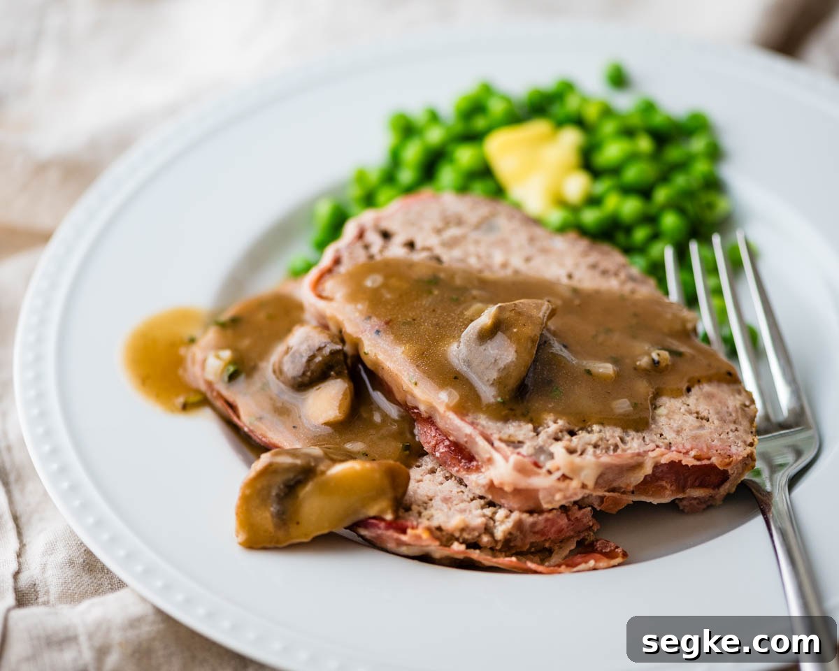 Oven Baked Meatloaf with Creamy Mushroom Gravy 7 meatloaf with mushroom gravy on a plate with peas.