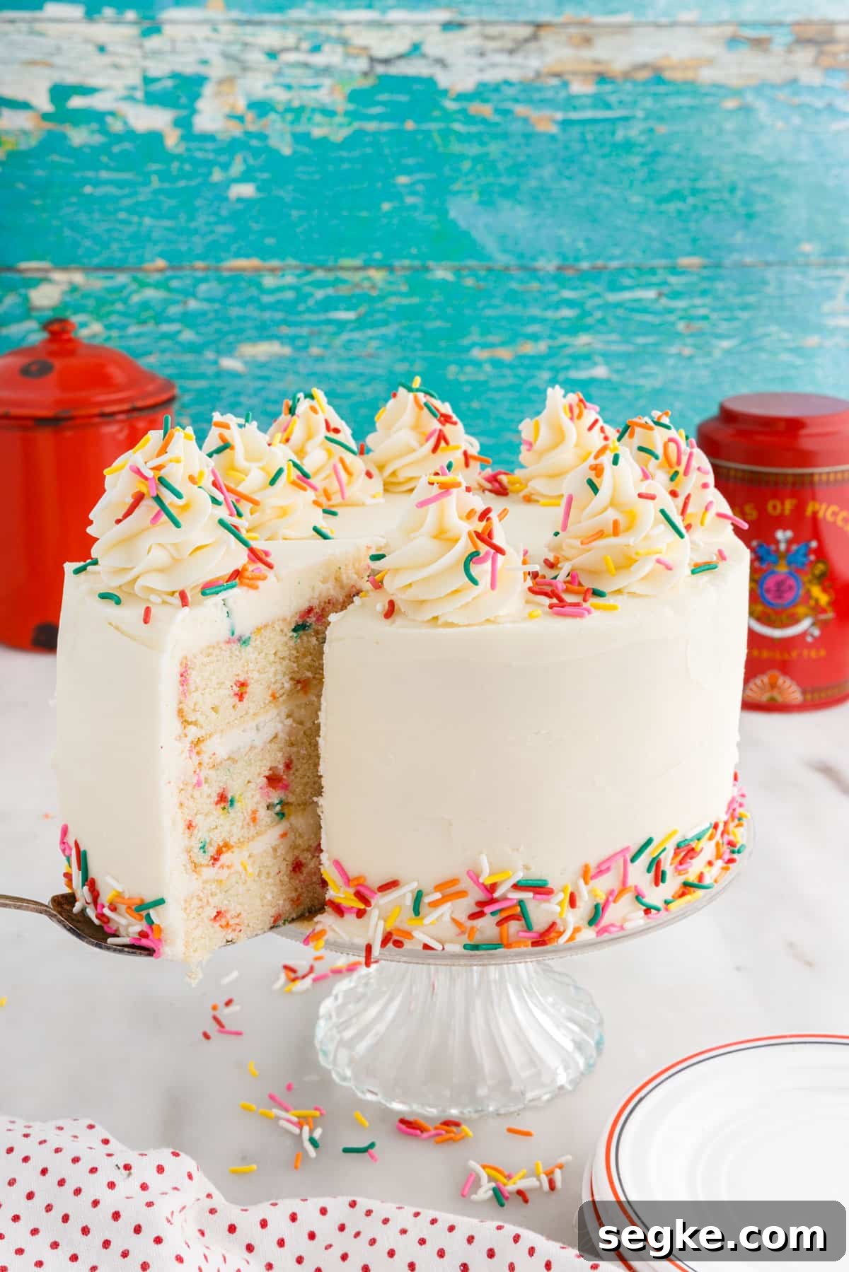 Funfetti Cake Recipe with Rainbow Sprinkles 16 A slice being taken from a Funfetti Cake.