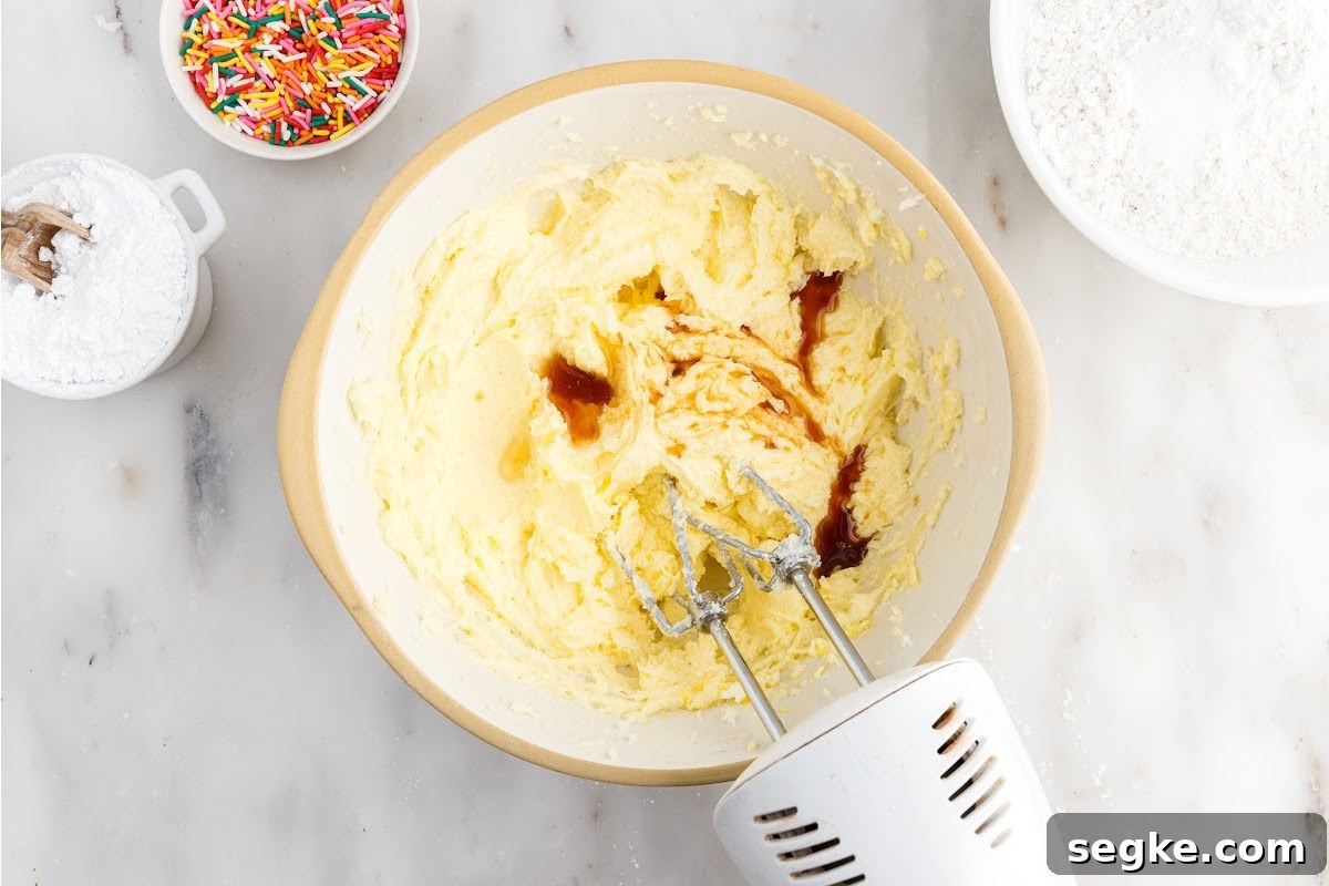 Funfetti Cake Recipe with Rainbow Sprinkles 5 Vanilla added to egg mixture in a mixing bowl mixed with a mixer.