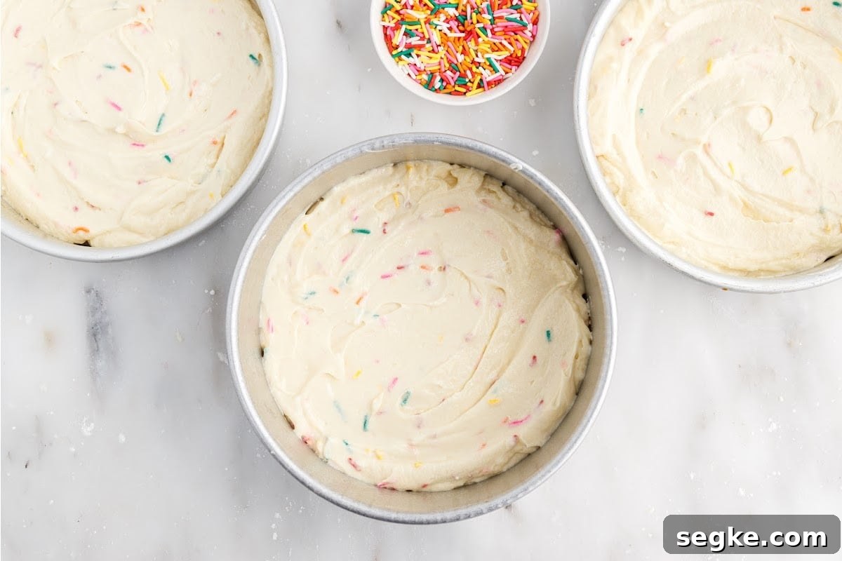 Funfetti Cake Recipe with Rainbow Sprinkles 9 Funfetti Cake batter separated into three pans next to a bowl of sprinkles.
