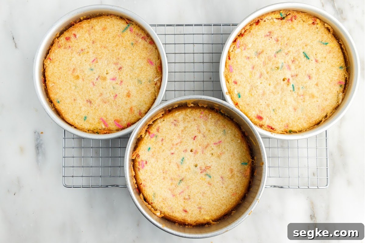 Funfetti Cake Recipe with Rainbow Sprinkles 10 Three pans of Funfetti Cake after being baked on a cooling rack.