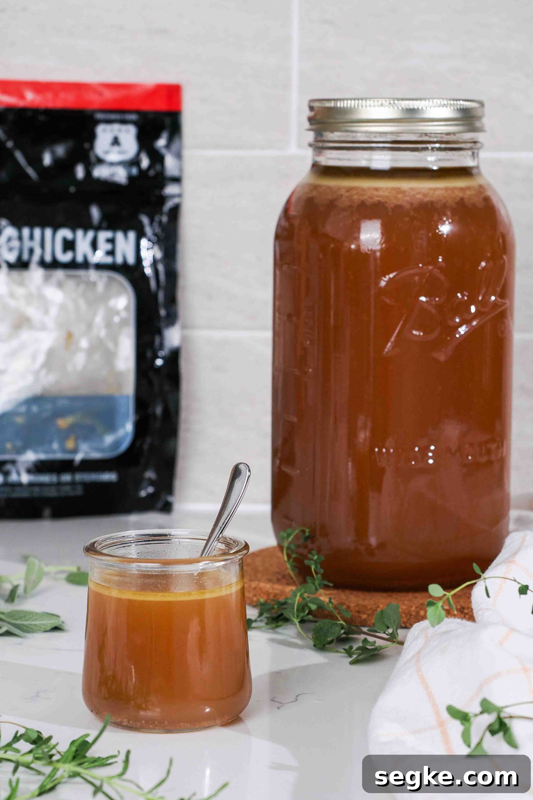 Instant Pot Chicken Bone Broth Recipe 2 Two jars of chicken broth on a counter, with a Costco chicken bag in the background.