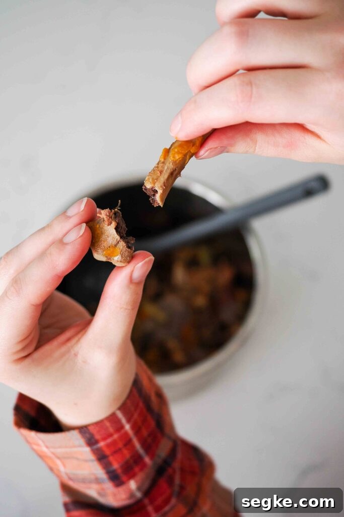 Instant Pot Chicken Bone Broth Recipe 11 Two hands snap a chicken bone in half easily.