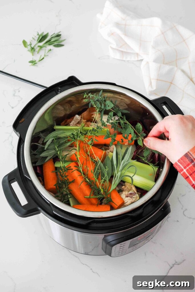 Instant Pot Chicken Bone Broth Recipe 6 A hand places fresh herbs into the pot of an Instant Pot.