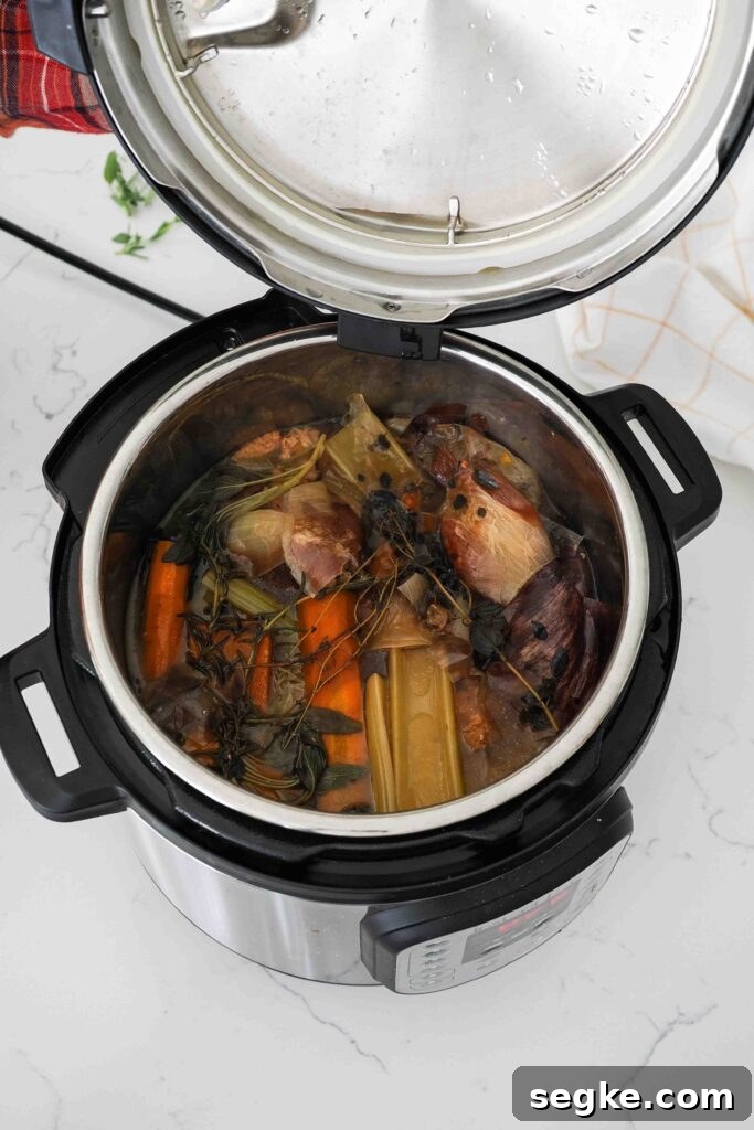 Instant Pot Chicken Bone Broth Recipe 9 Wilted vegetables and herbs in an Instant Pot with chicken broth.