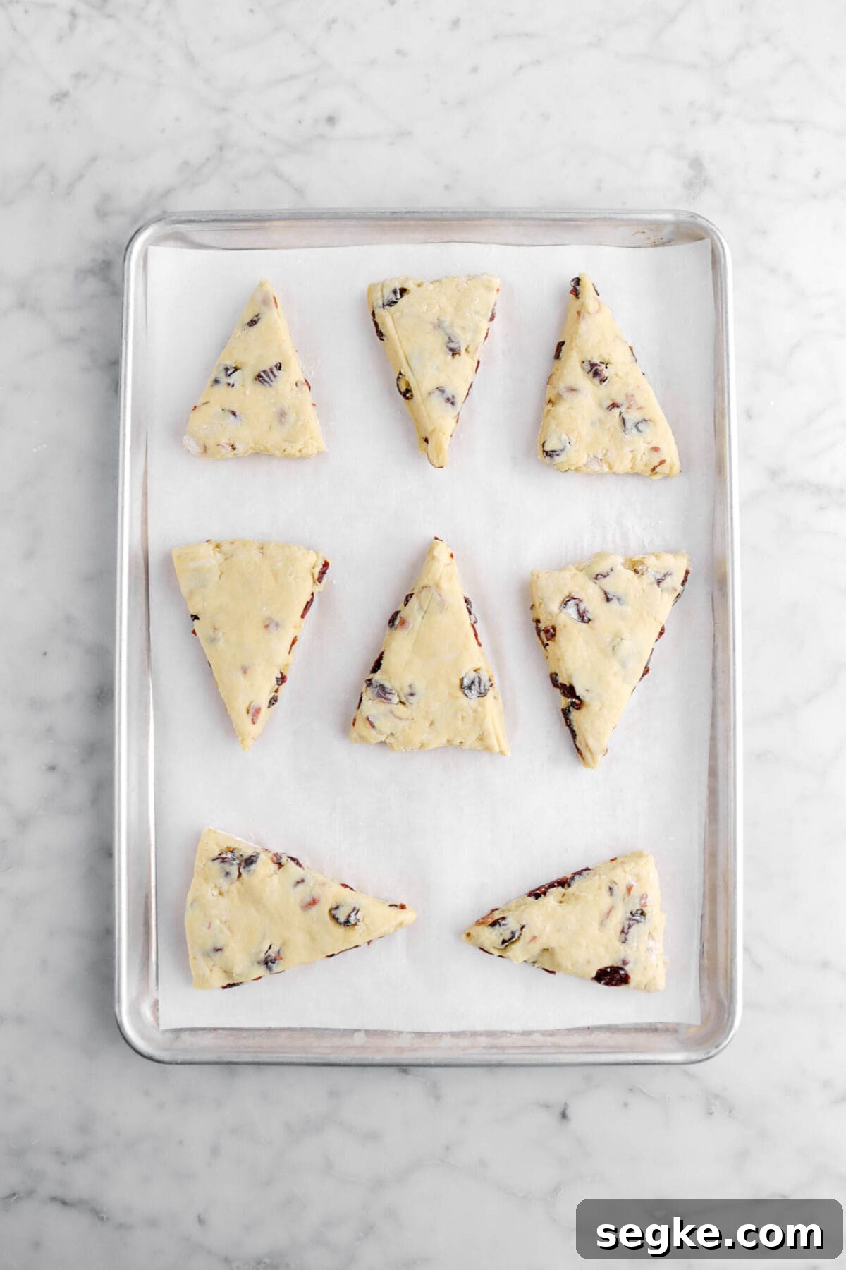 eight unbaked scones on lined sheet pan.