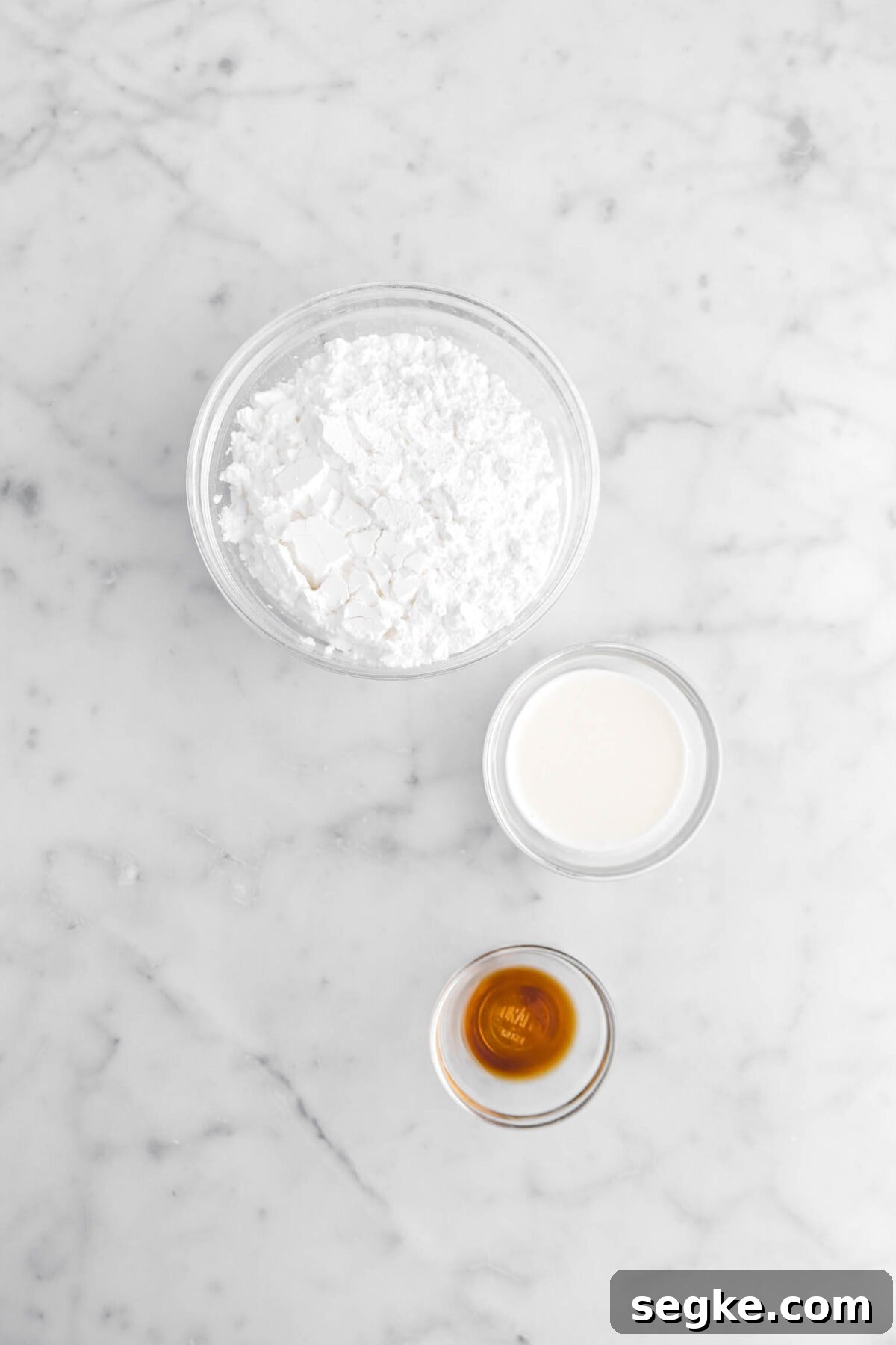 powdered sugar, milk, and vanilla on marble surface.