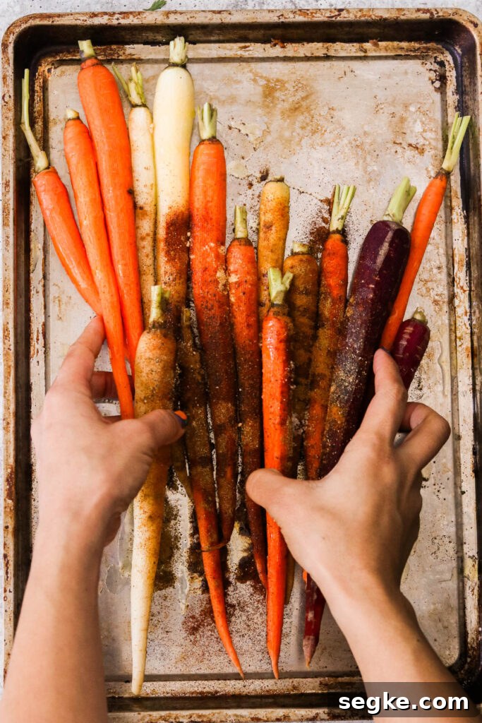 hands placing carrots on a sheet pan 