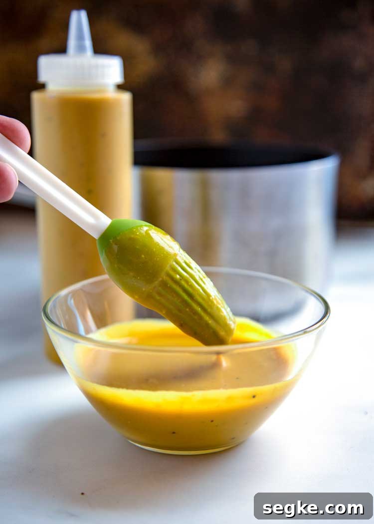 dipping basting brush into dish of Carolina gold sauce