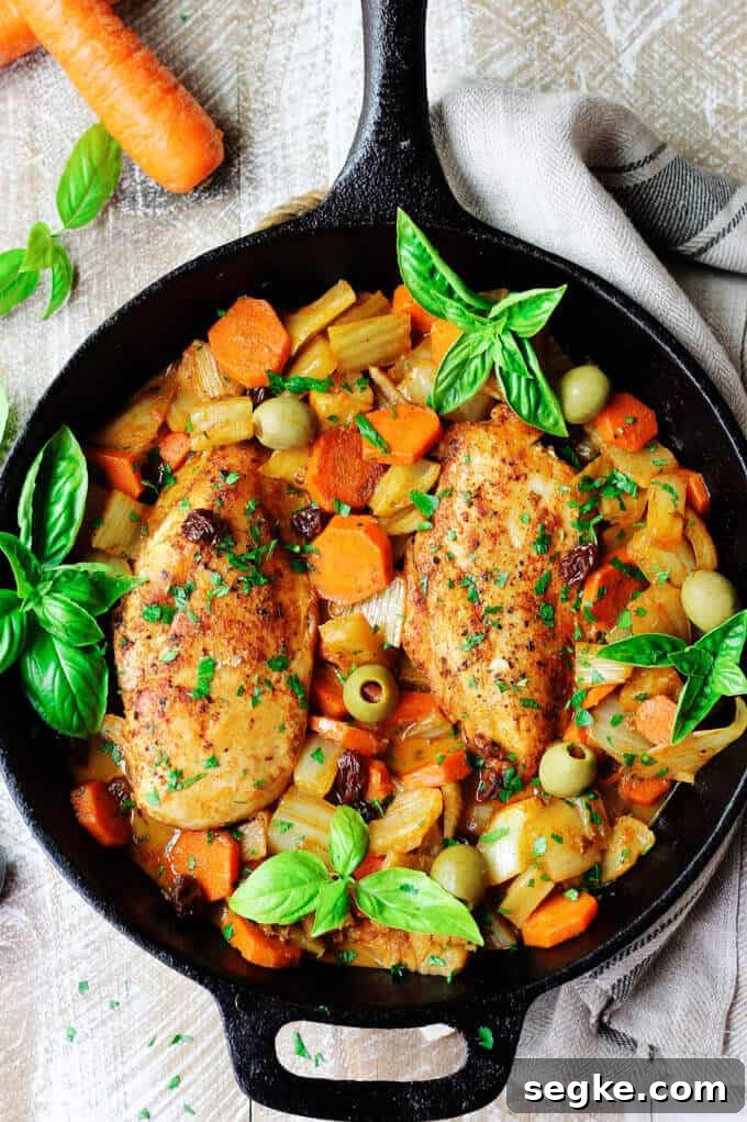 Fennel Chicken Mediterranean Style with carrots, raisins and olives is a very easy, one pot meal recipe for any day of the week. It is seasoned with cinnamon, cumin and smoked paprika for an irresistible and flavorful chicken dish. Overhead photo of Fennel Chicken Mediterranean Style with basil