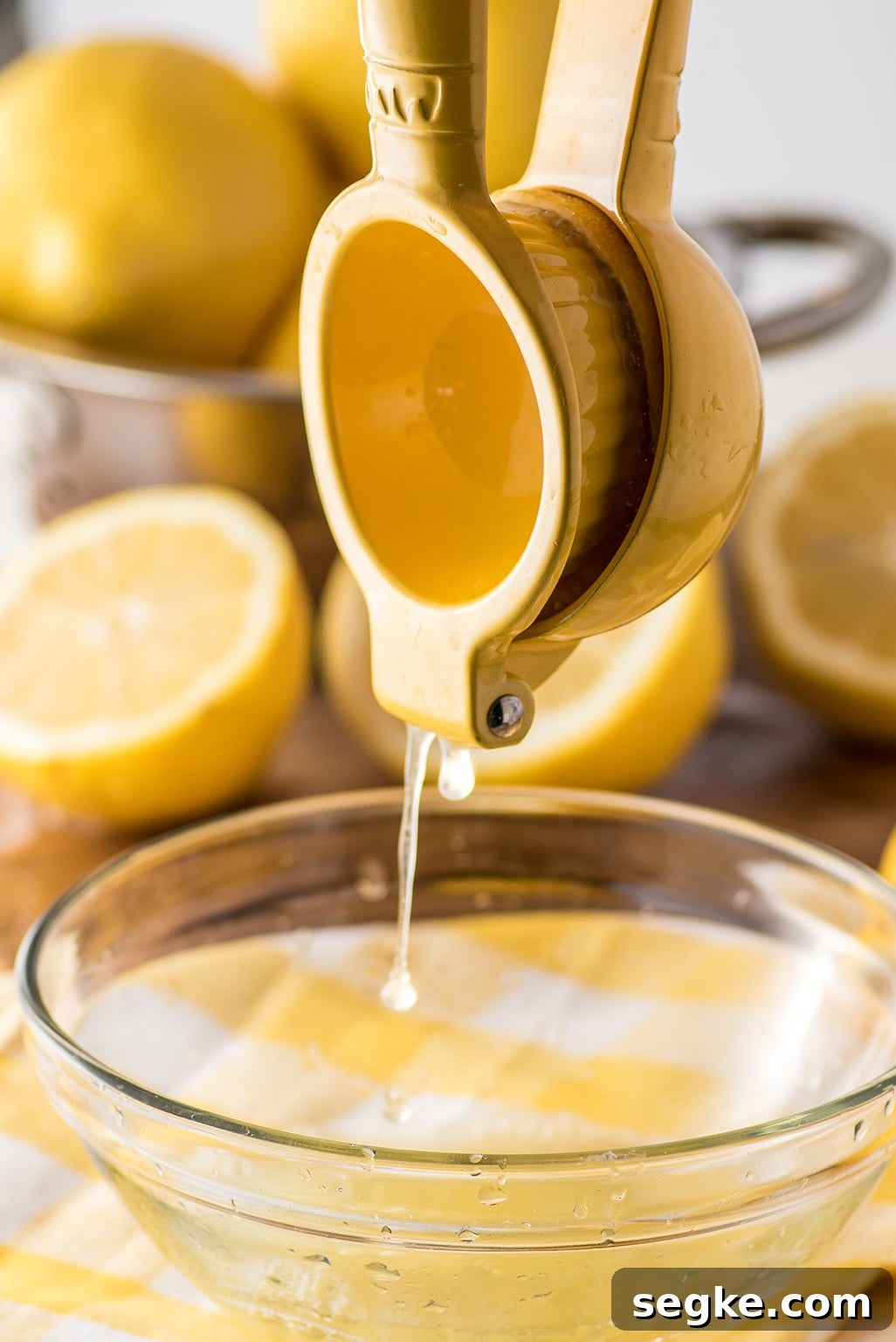 Quick Keto Lemon Curd Recipe: Zesty Low-Carb Spread 3 A yellow juice presser with fresh lemon juice dripping into a clear bowl on top of a yellow gingham napkin. A bowl of fresh whole and slice lemons are in the background.
