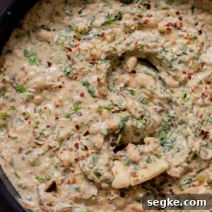 close-up of a panful of Tuscan beans with a piece of flatbread dipped into it
