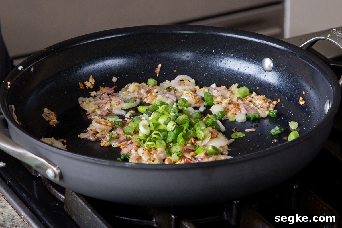 One-Pan Tuscan White Bean Skillet Recipe 7 adding green onion to the pan of cooked garlic and onions
