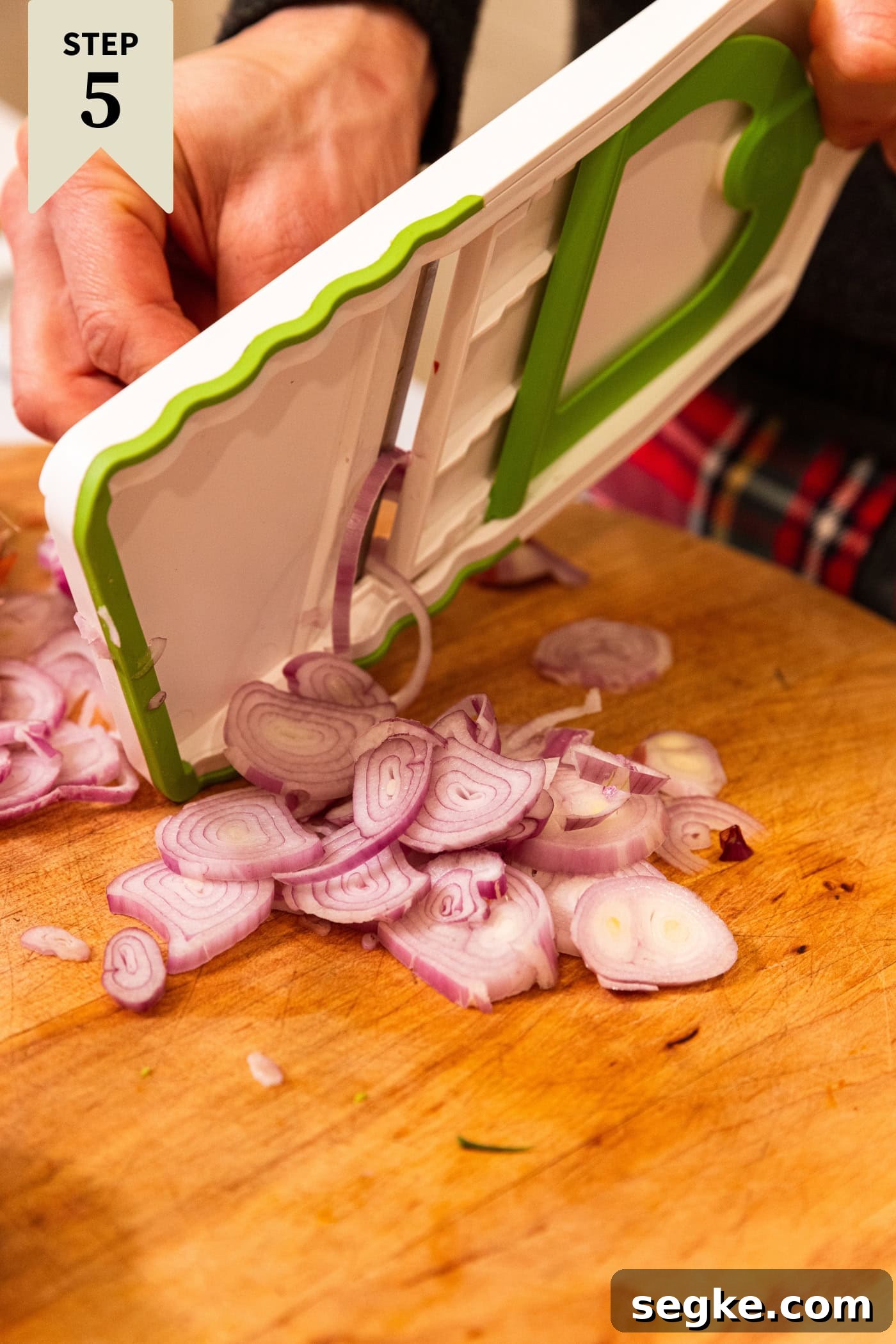 Creamy Homemade Green Bean Casserole Recipe 11 Mandolin slicing scallion into small pieces on a wooden cutting board.