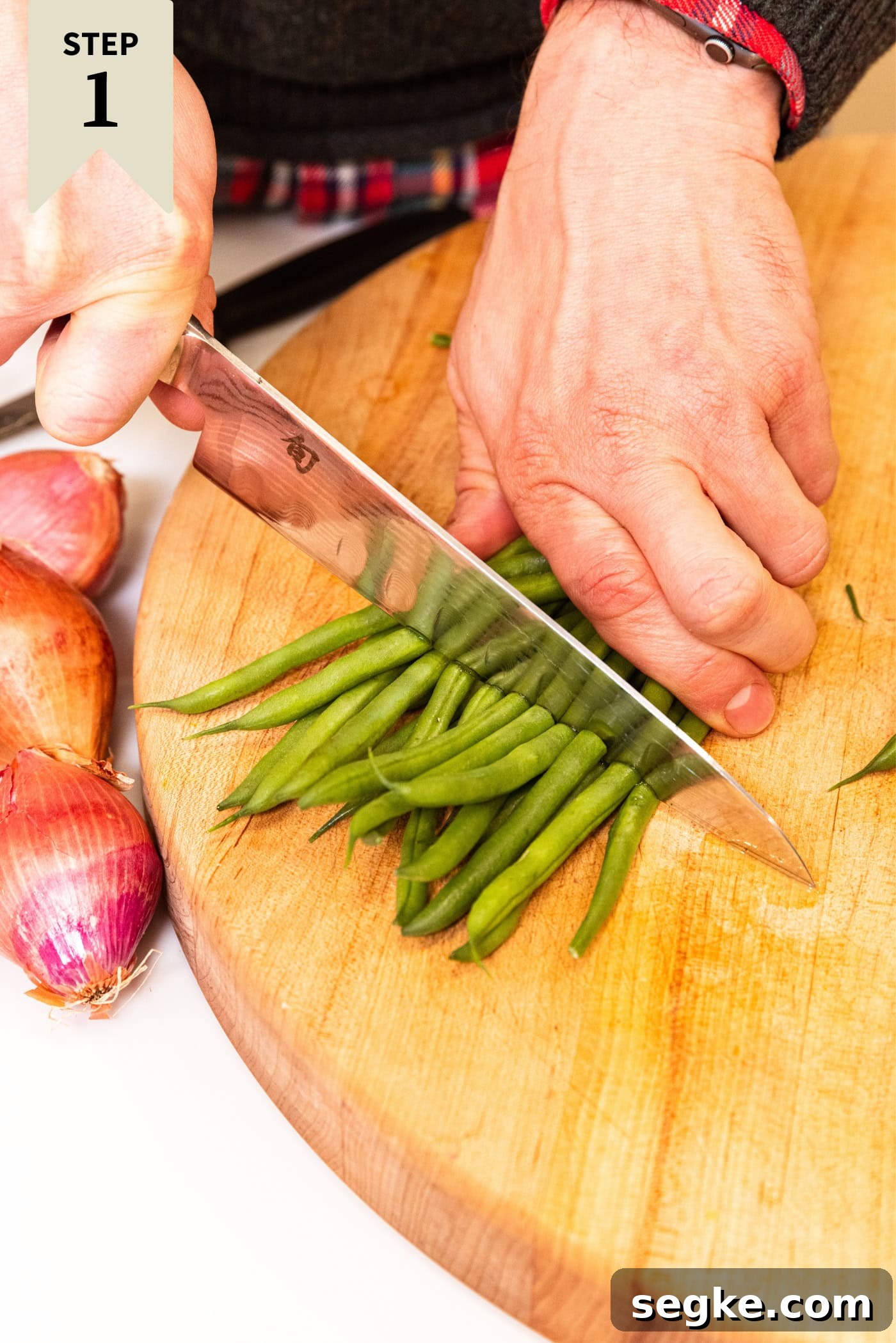 Creamy Homemade Green Bean Casserole Recipe 5 Hand using a knife to cut green beans in half for a green bean casserole.