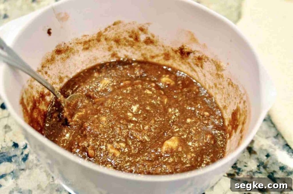 Close-up of cinnamon filling mixture in a white bowl with a spoon.