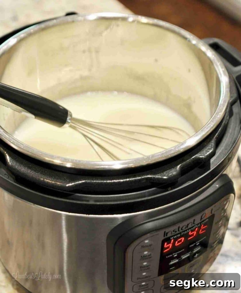 Cream cheese frosting being mixed in an Instant Pot with a whisk.