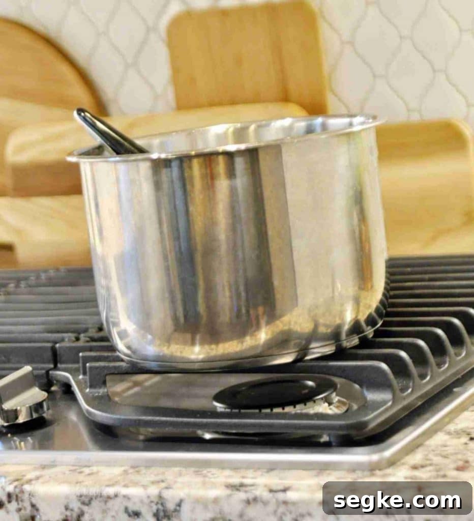 Stainless steel pot on stovetop with wooden cutting boards in background.