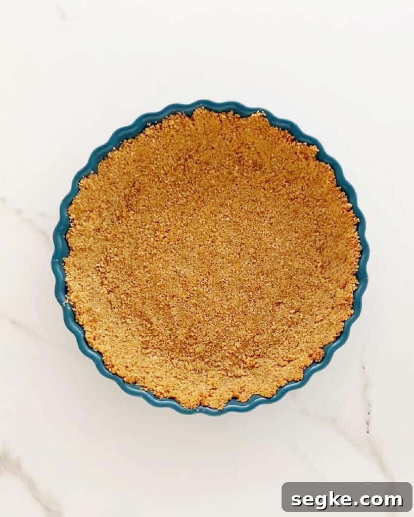 No-Bake Pineapple Cream Cheese Pie 5 Teal pie dish with graham cracker crust on a white marbled surface.