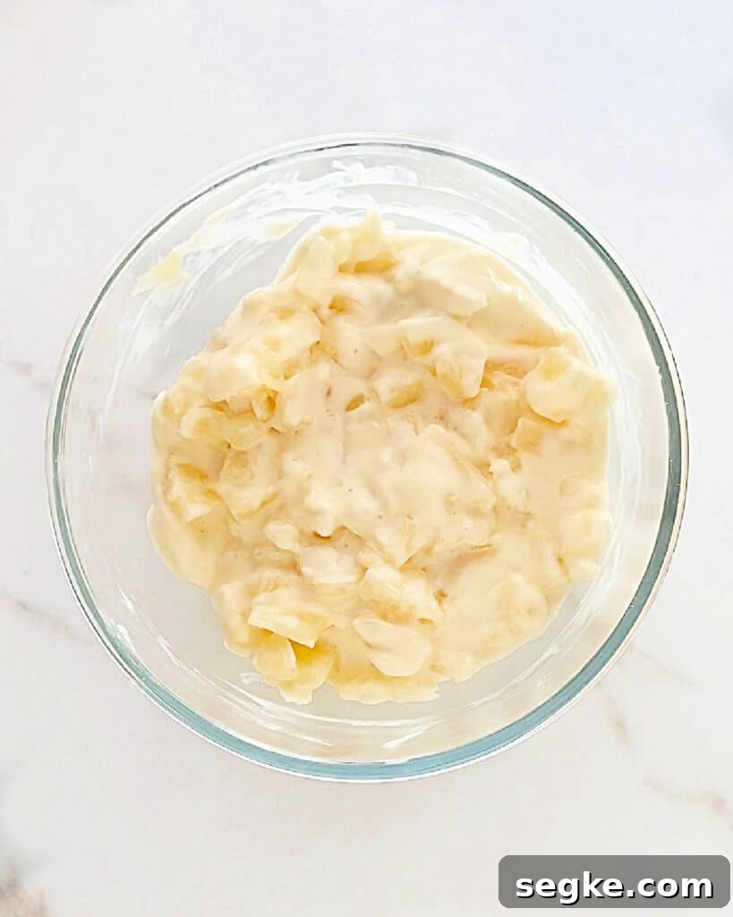 No-Bake Pineapple Cream Cheese Pie 7 Glass bowl with cream cheese pineapple mixture. White background, top view.