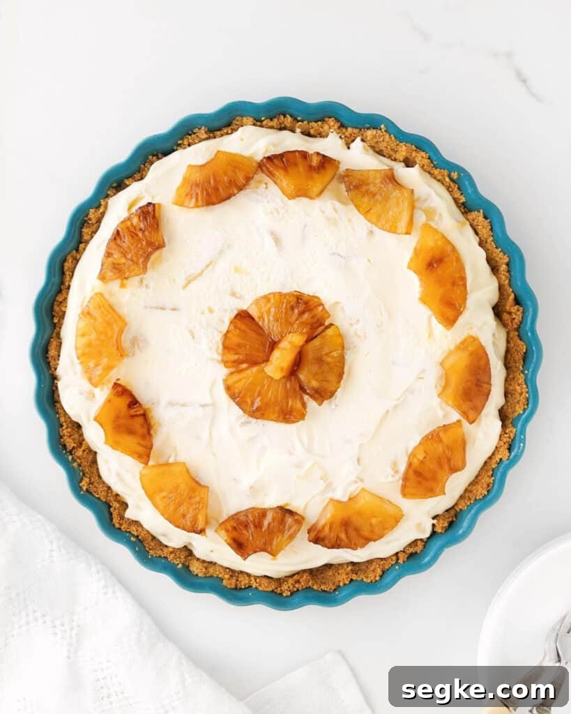 No-Bake Pineapple Cream Cheese Pie 10 Whole pineapple cream cheese pie in a teal dish. Top view on a white surface.