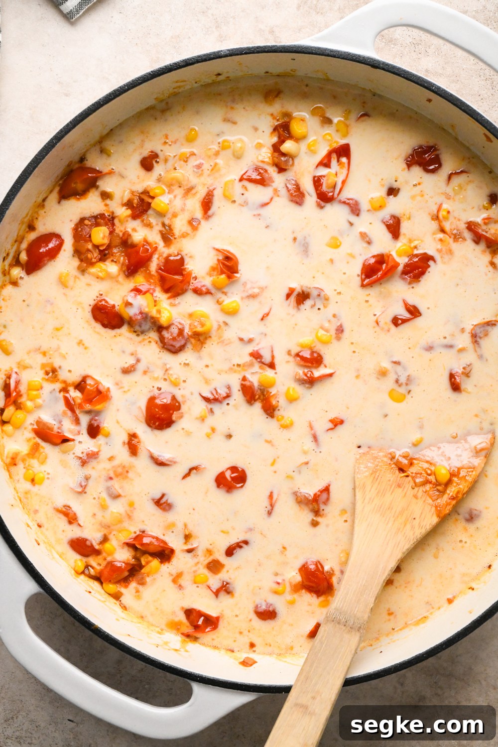The white skillet just after adding the cashew cream mixture to the tomatoes and corn.