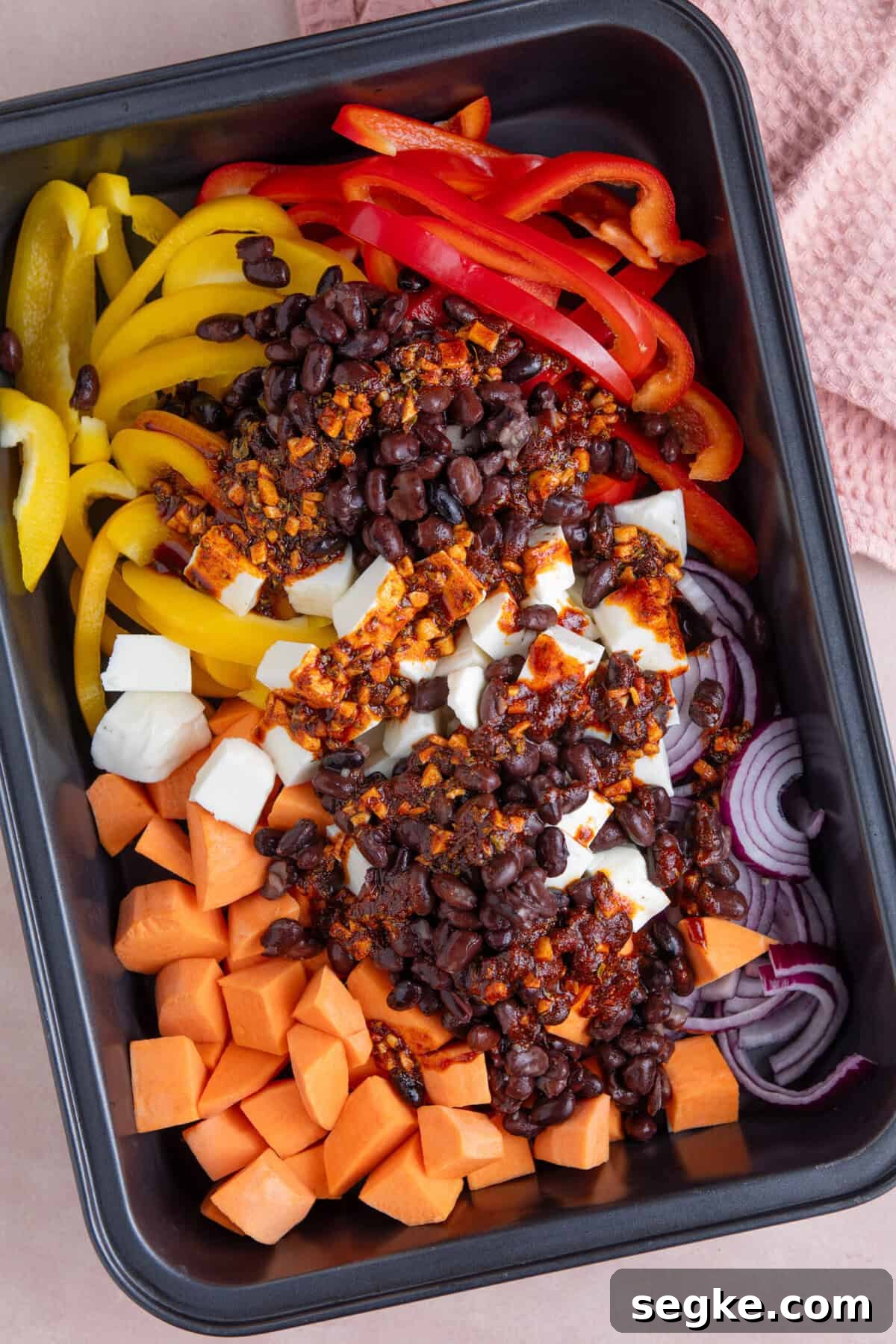 Sheet Pan Halloumi Tacos with Roasted Vegetables 6 Process shot for halloumi tacos recipe showing the marinade poured onto the ingredients in a tray.