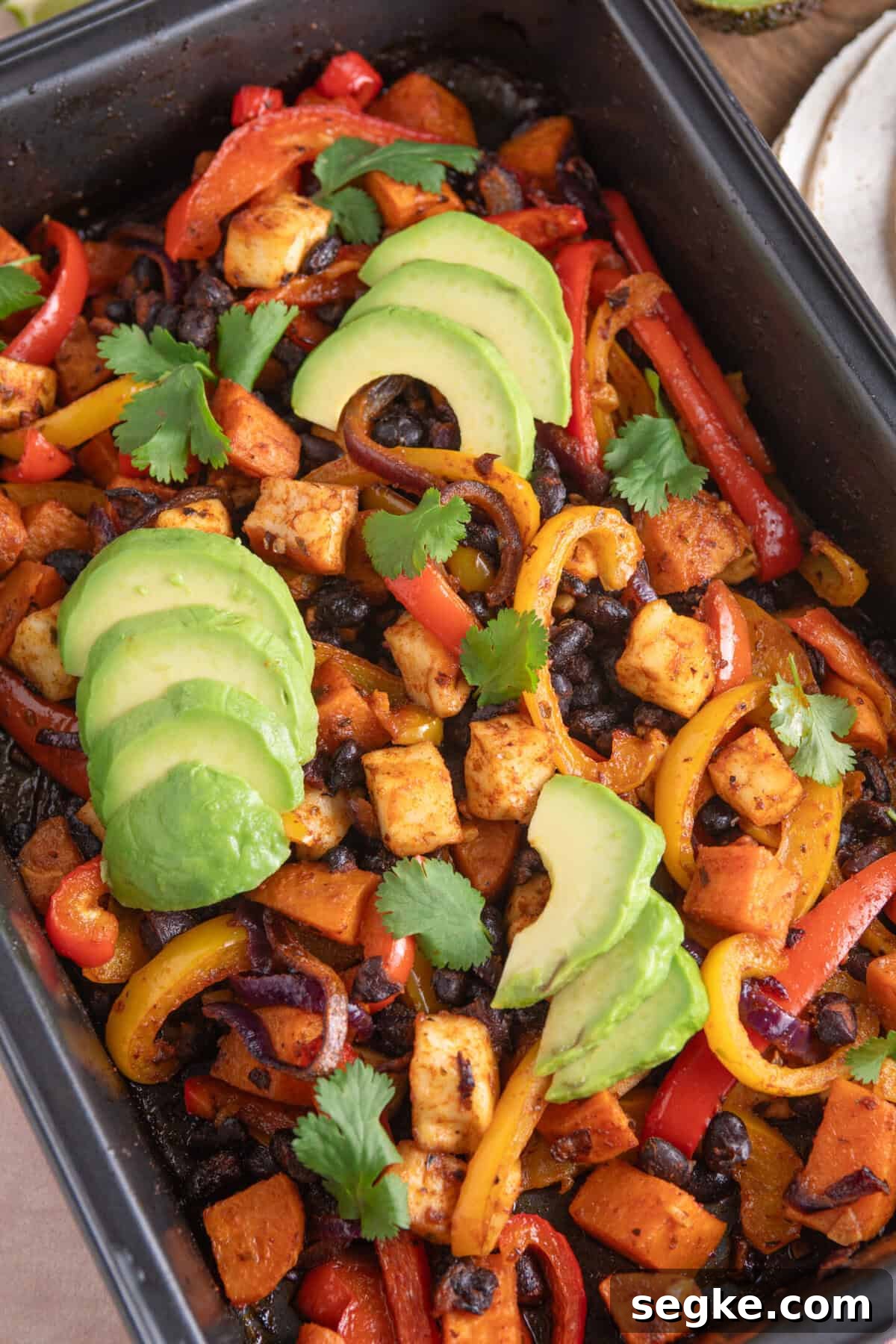 Sheet Pan Halloumi Tacos with Roasted Vegetables 8 Overhead shot of halloumi taco fillings in a baking tray, with sweet potato, black beans and peppers.