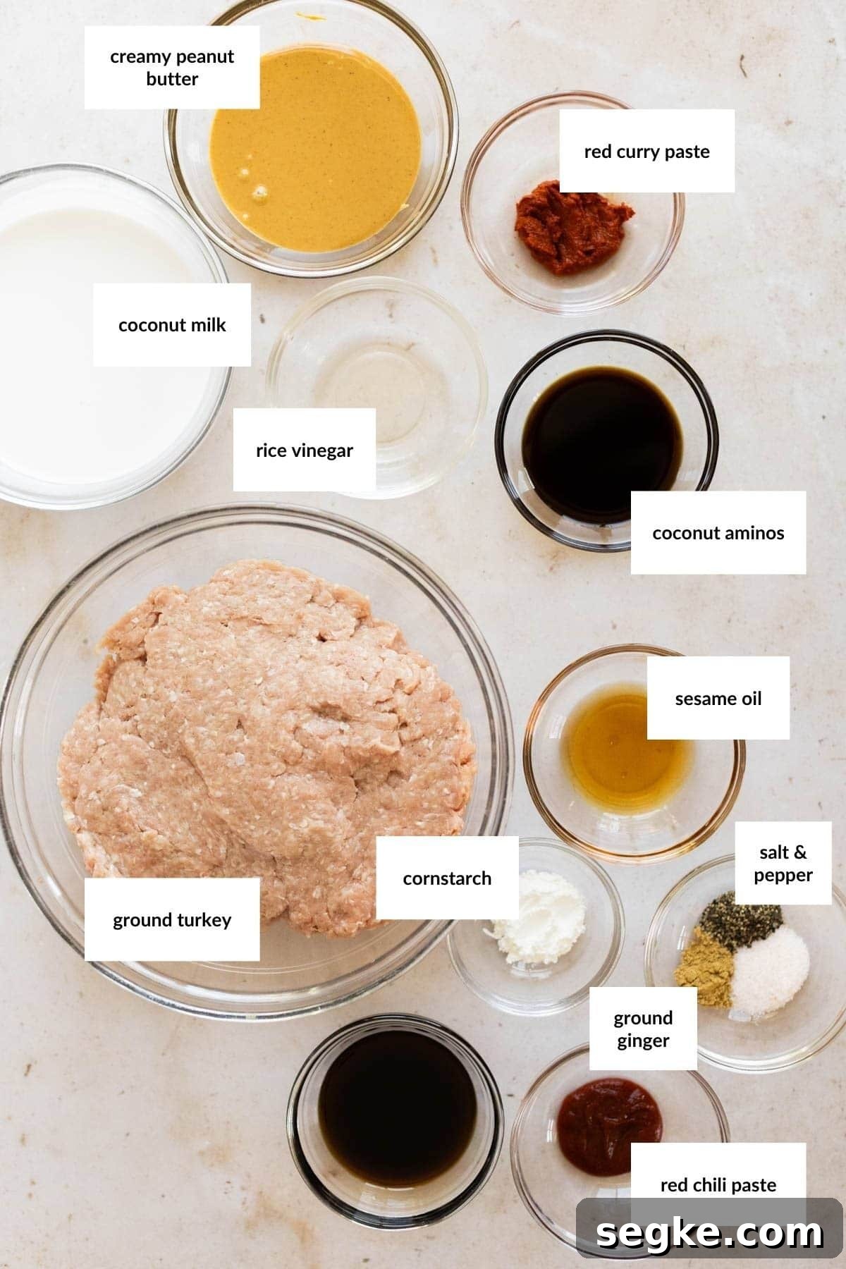 Ground Turkey Lettuce Wraps with Ginger-Soy Sauce 2 Top-down view of labeled bowls with ingredients for turkey lettuce wraps, including ground turkey, coconut milk, peanut butter, curry paste, vinegar, aminos, sesame oil, cornstarch, spices, and ginger.