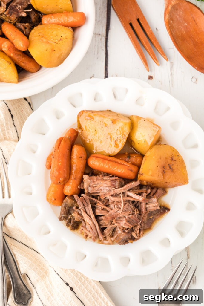 portion of roast beef with potatoes and carrots on white plate
