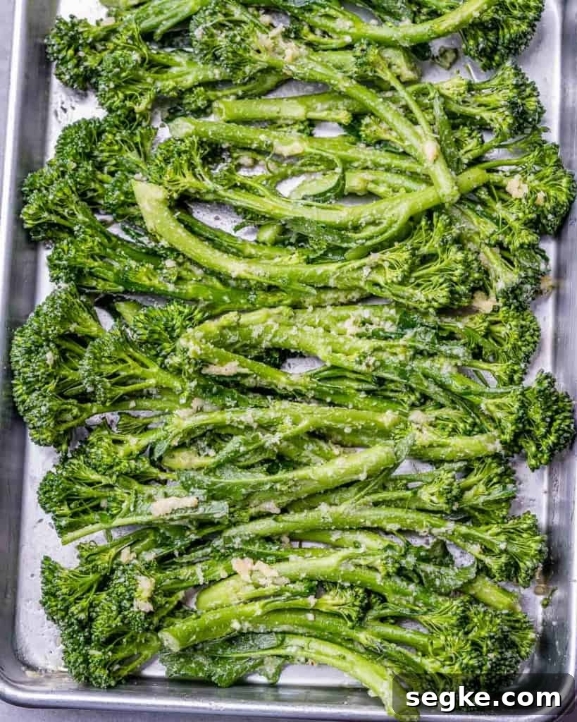seasoned broccolini added to pan before roasting 