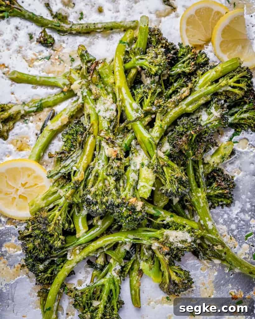 top view roasted broccolini on a pan with lemon garnished and parmesan cheese
