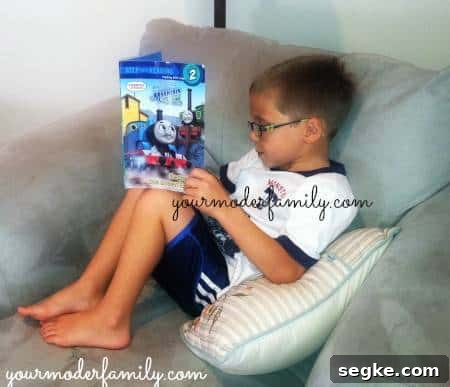 Learning Through Play: Activities That Boost Kids' Skills 3 A little boy reading a Thomas the Tank book on the couch.